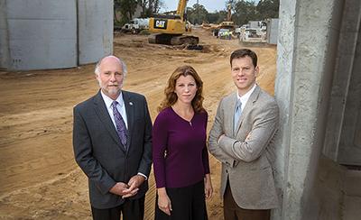 From left, Tallahassee City Commissioner Gil Ziffer, Leon County Commissioner Kristin Dozier and Kevin Graham, executive director of FSU’s Real Estate Foundation, represent key partners in the multilayered Gateway District project. They were photographed at the FAMU Way Extension construction site — a key connector among the airport, the universities and downtown. Photo Credit: Bruce Palmer